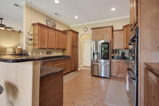 kitchen with light tile patterned flooring, stainless steel fridge, ornamental molding, and kitchen peninsula