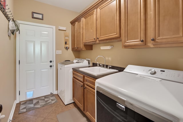 laundry area featuring washing machine and dryer, cabinets, sink, and light tile patterned floors