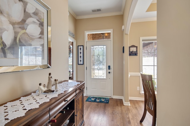 foyer with crown molding and light hardwood / wood-style floors