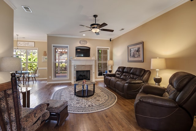 living room featuring ceiling fan, crown molding, dark hardwood / wood-style flooring, and a tile fireplace