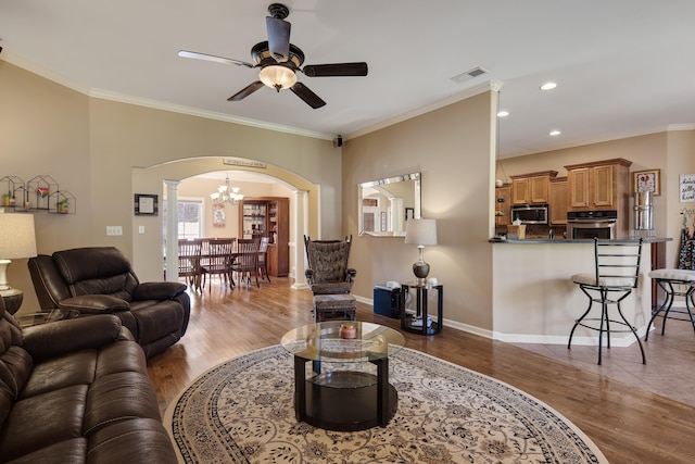 living room featuring ceiling fan with notable chandelier, ornamental molding, and hardwood / wood-style flooring