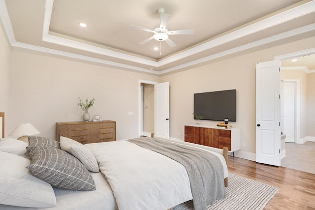 bedroom with ceiling fan, hardwood / wood-style flooring, a raised ceiling, and ornamental molding