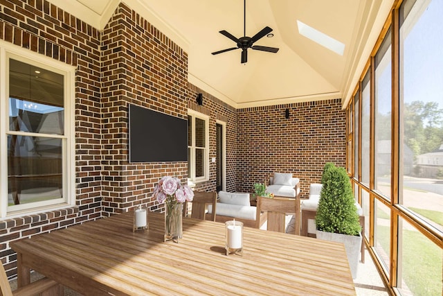 unfurnished sunroom featuring ceiling fan and lofted ceiling with skylight