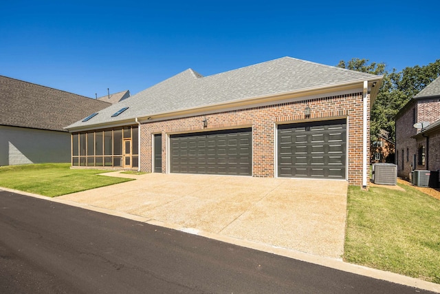 view of front of home featuring a garage, a sunroom, a front lawn, and central air condition unit