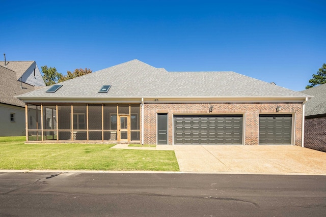 view of front of home featuring a sunroom, a front yard, and a garage