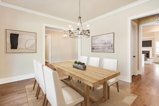 dining space with hardwood / wood-style flooring, crown molding, and a chandelier