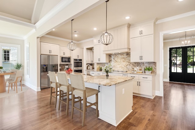 kitchen with appliances with stainless steel finishes, plenty of natural light, white cabinetry, and an island with sink