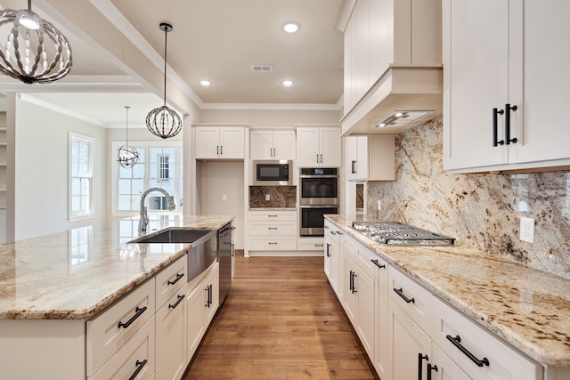 kitchen featuring light wood-type flooring, sink, decorative light fixtures, white cabinetry, and light stone countertops