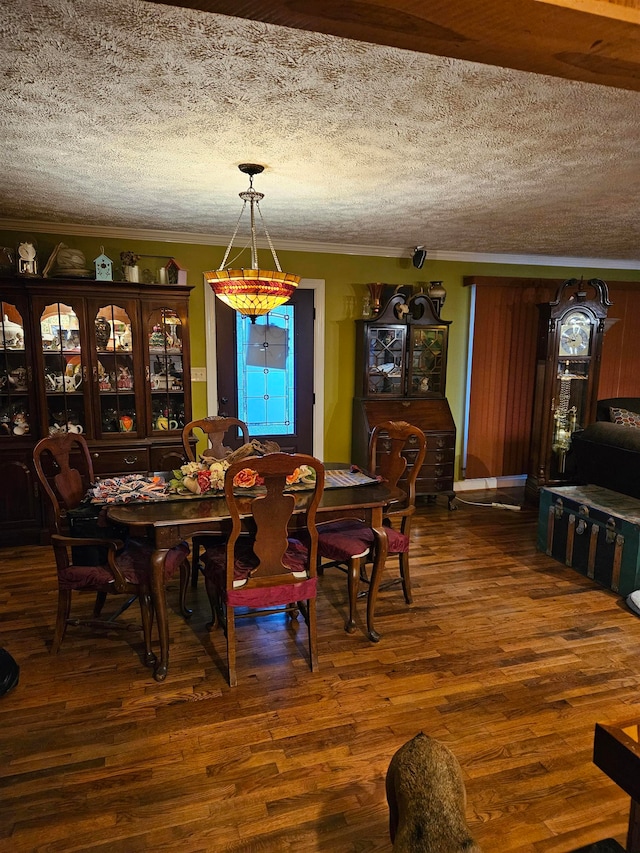 dining room with ornamental molding, dark wood-type flooring, and a textured ceiling