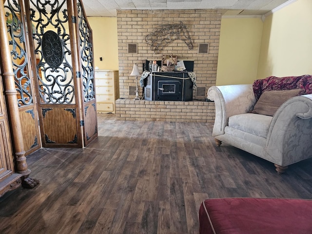 living room with crown molding, dark hardwood / wood-style flooring, and a wood stove