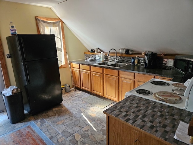 kitchen with black fridge, lofted ceiling, and sink