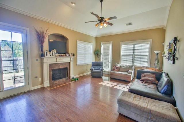 living room with ceiling fan, wood-type flooring, vaulted ceiling, ornamental molding, and a fireplace