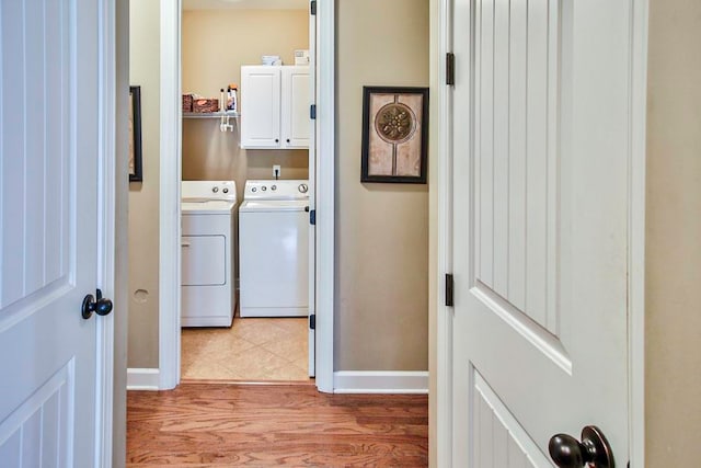 laundry room featuring light hardwood / wood-style floors, independent washer and dryer, and cabinets