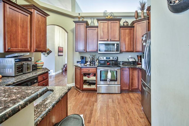 kitchen featuring light hardwood / wood-style flooring, dark stone countertops, and stainless steel appliances