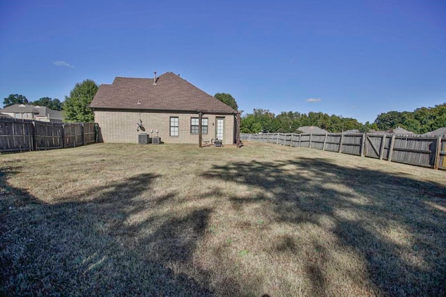 rear view of house featuring central air condition unit and a lawn