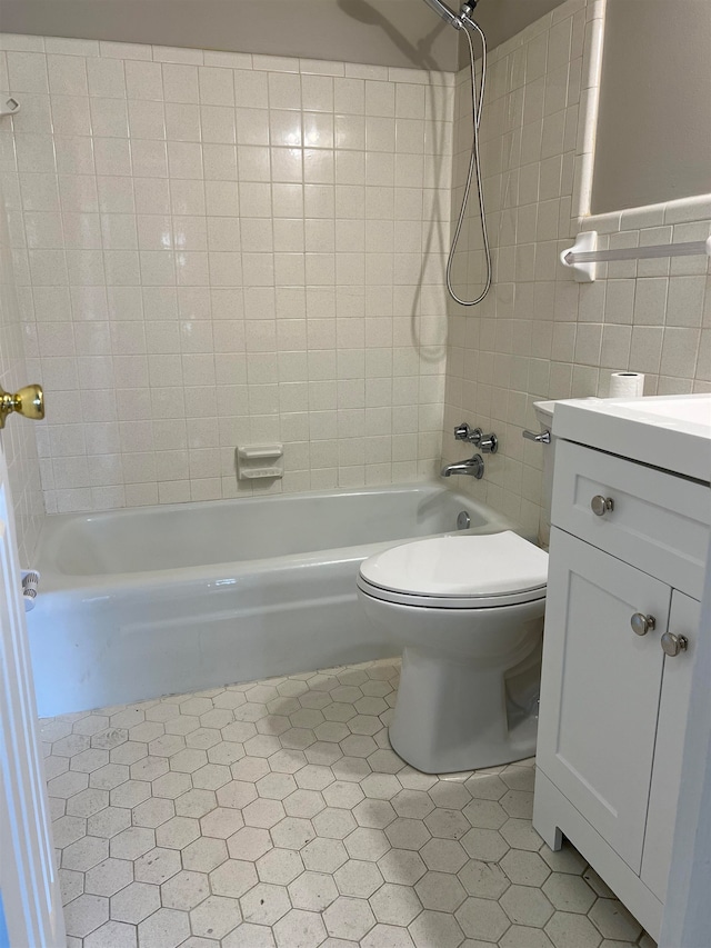 full bathroom featuring vanity, tile walls, toilet, and tiled shower / bath combo