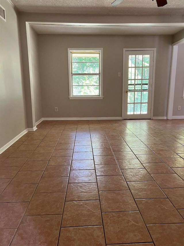 tiled spare room with ceiling fan and a textured ceiling