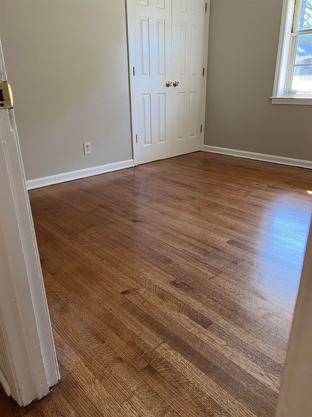 unfurnished bedroom with dark wood-type flooring and a closet