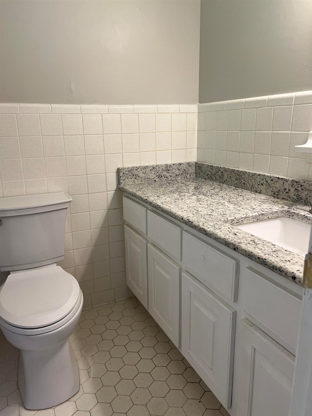 bathroom featuring tile patterned flooring, vanity, tile walls, and toilet