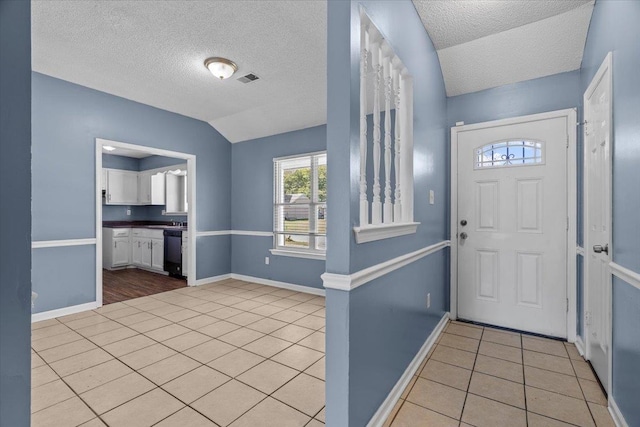 tiled foyer featuring vaulted ceiling and a textured ceiling