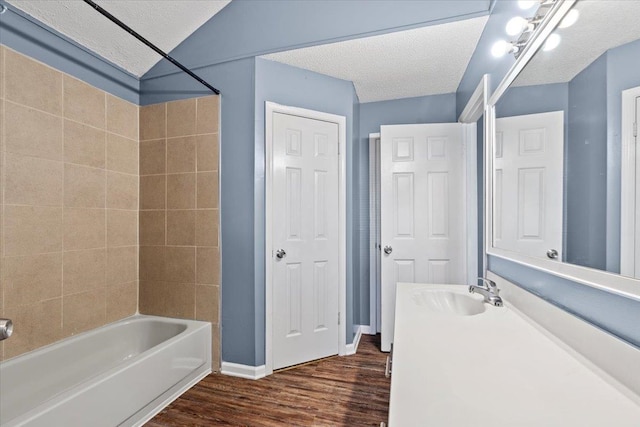 bathroom featuring vanity, tiled shower / bath, hardwood / wood-style flooring, and a textured ceiling