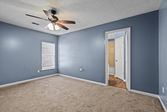 carpeted empty room featuring ceiling fan and a textured ceiling