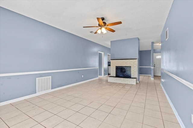 unfurnished living room with ceiling fan, a textured ceiling, a fireplace, and light tile patterned floors