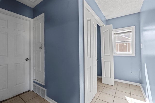 hall featuring light tile patterned flooring and a textured ceiling