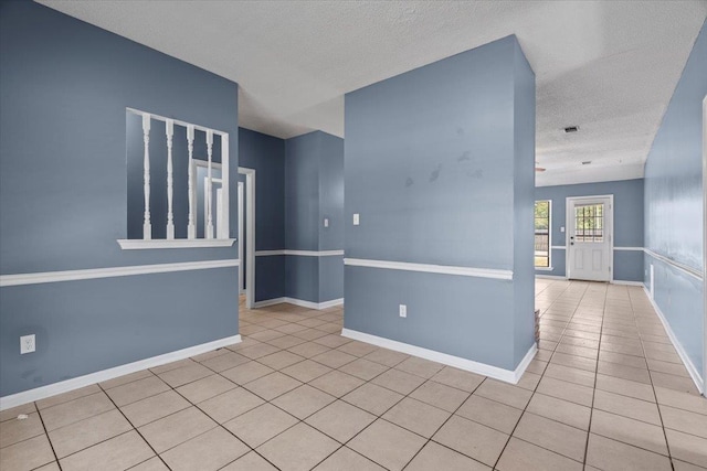 empty room featuring light tile patterned flooring and a textured ceiling