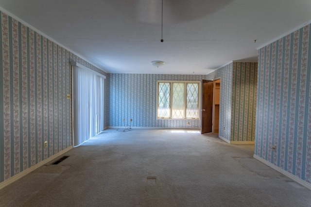 empty room featuring crown molding and carpet floors