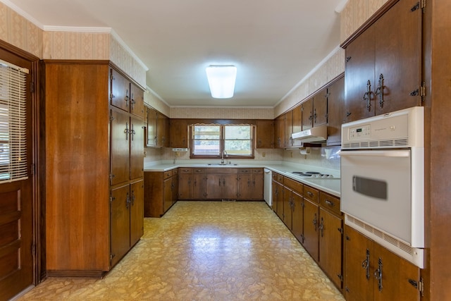 kitchen with sink, ornamental molding, white appliances, and tasteful backsplash