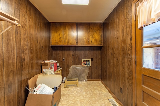 clothes washing area with ornamental molding, washer hookup, wood walls, and cabinets