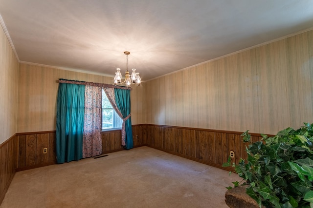 carpeted empty room featuring a notable chandelier, wooden walls, and crown molding