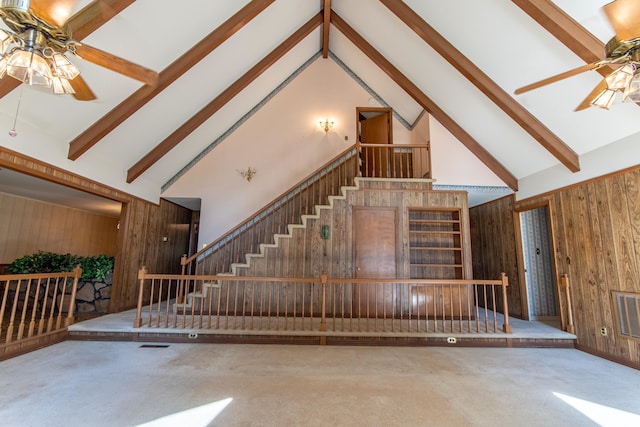 staircase with beam ceiling, high vaulted ceiling, and wooden walls