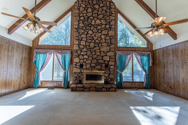 unfurnished living room featuring wooden walls, high vaulted ceiling, and a wealth of natural light