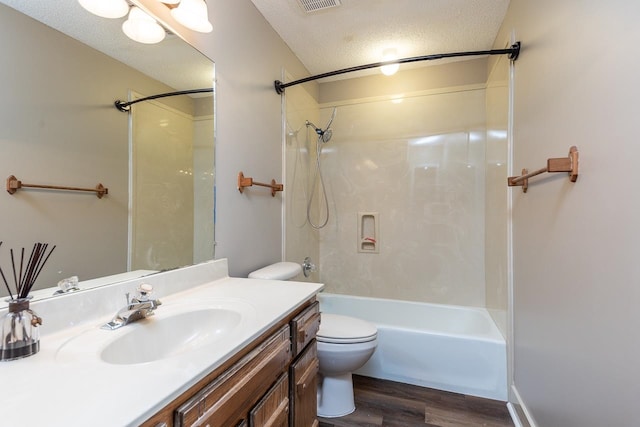 full bathroom featuring hardwood / wood-style floors, vanity, shower / washtub combination, toilet, and a textured ceiling