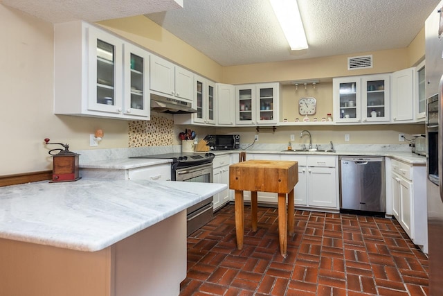 kitchen featuring appliances with stainless steel finishes, a textured ceiling, sink, and white cabinets