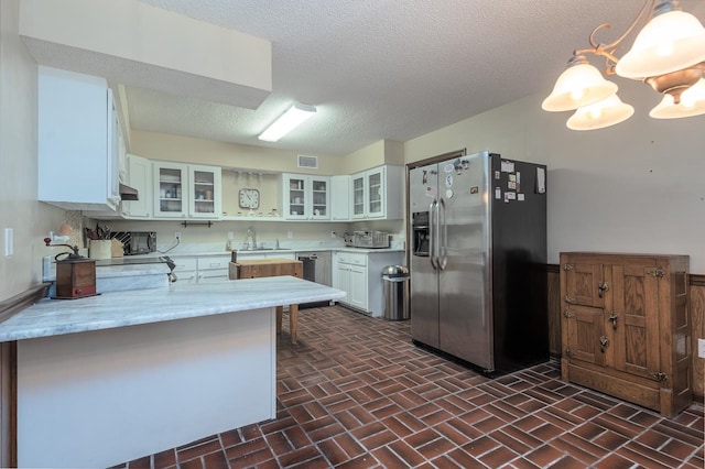 kitchen with pendant lighting, white cabinets, kitchen peninsula, a textured ceiling, and stainless steel refrigerator with ice dispenser