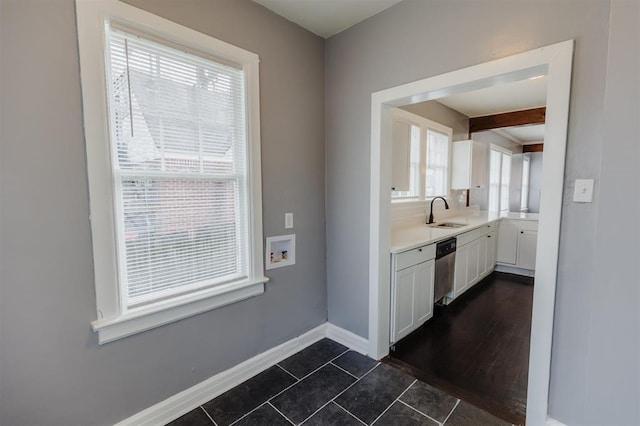 kitchen with beamed ceiling, stainless steel dishwasher, dark hardwood / wood-style floors, white cabinets, and sink