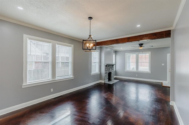 unfurnished dining area featuring dark wood-type flooring, ceiling fan with notable chandelier, a fireplace, crown molding, and a textured ceiling