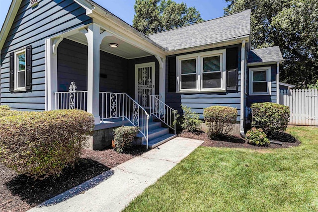 view of exterior entry featuring a yard and covered porch