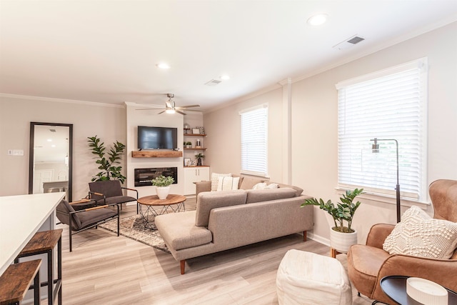 living room featuring ceiling fan, crown molding, and light hardwood / wood-style floors