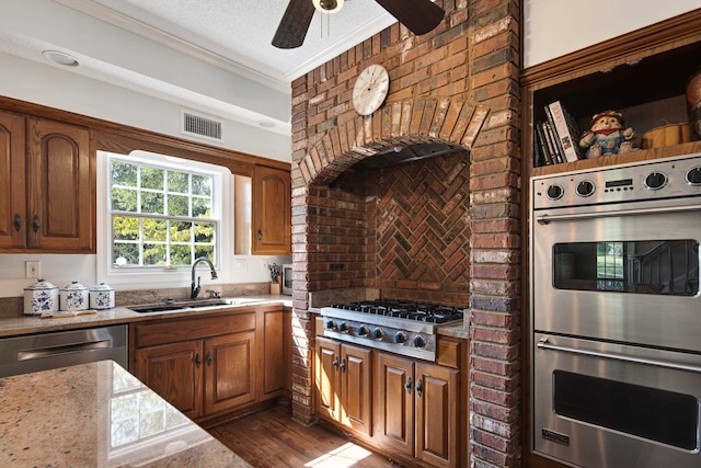 kitchen with ornamental molding, appliances with stainless steel finishes, a textured ceiling, dark hardwood / wood-style flooring, and sink