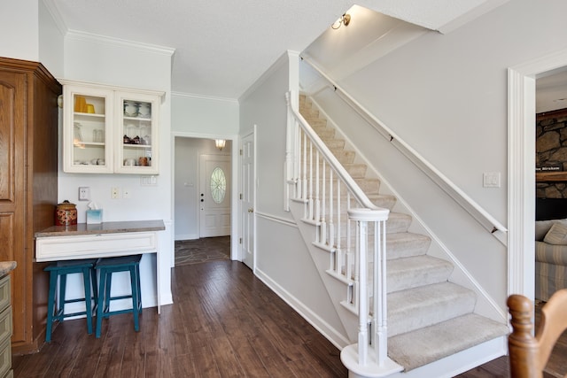 staircase with wood-type flooring, a textured ceiling, and ornamental molding