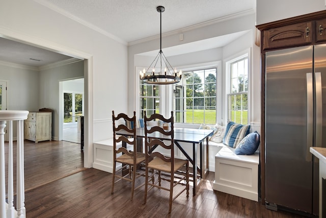 dining area with dark hardwood / wood-style floors, a textured ceiling, a notable chandelier, and ornamental molding