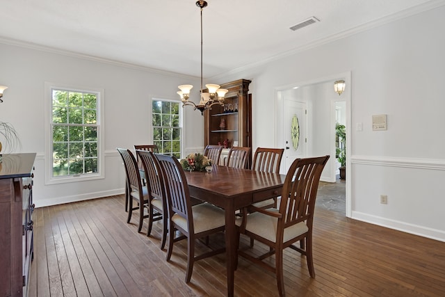 dining space with dark hardwood / wood-style flooring, an inviting chandelier, and crown molding