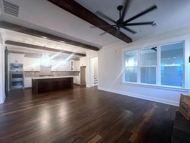 unfurnished living room featuring beamed ceiling, ceiling fan, and dark wood-type flooring