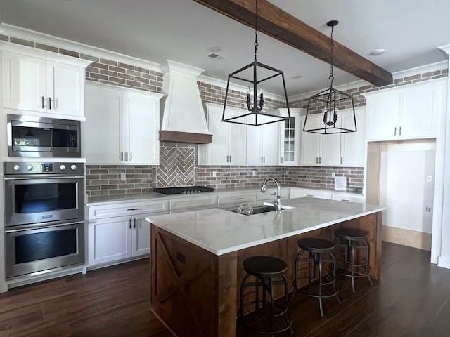 kitchen with white cabinetry, a kitchen island with sink, and dark hardwood / wood-style flooring