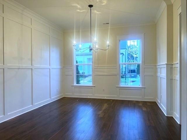 unfurnished dining area featuring crown molding, dark hardwood / wood-style floors, and an inviting chandelier