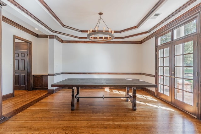 dining area with crown molding, a raised ceiling, a notable chandelier, french doors, and hardwood / wood-style flooring